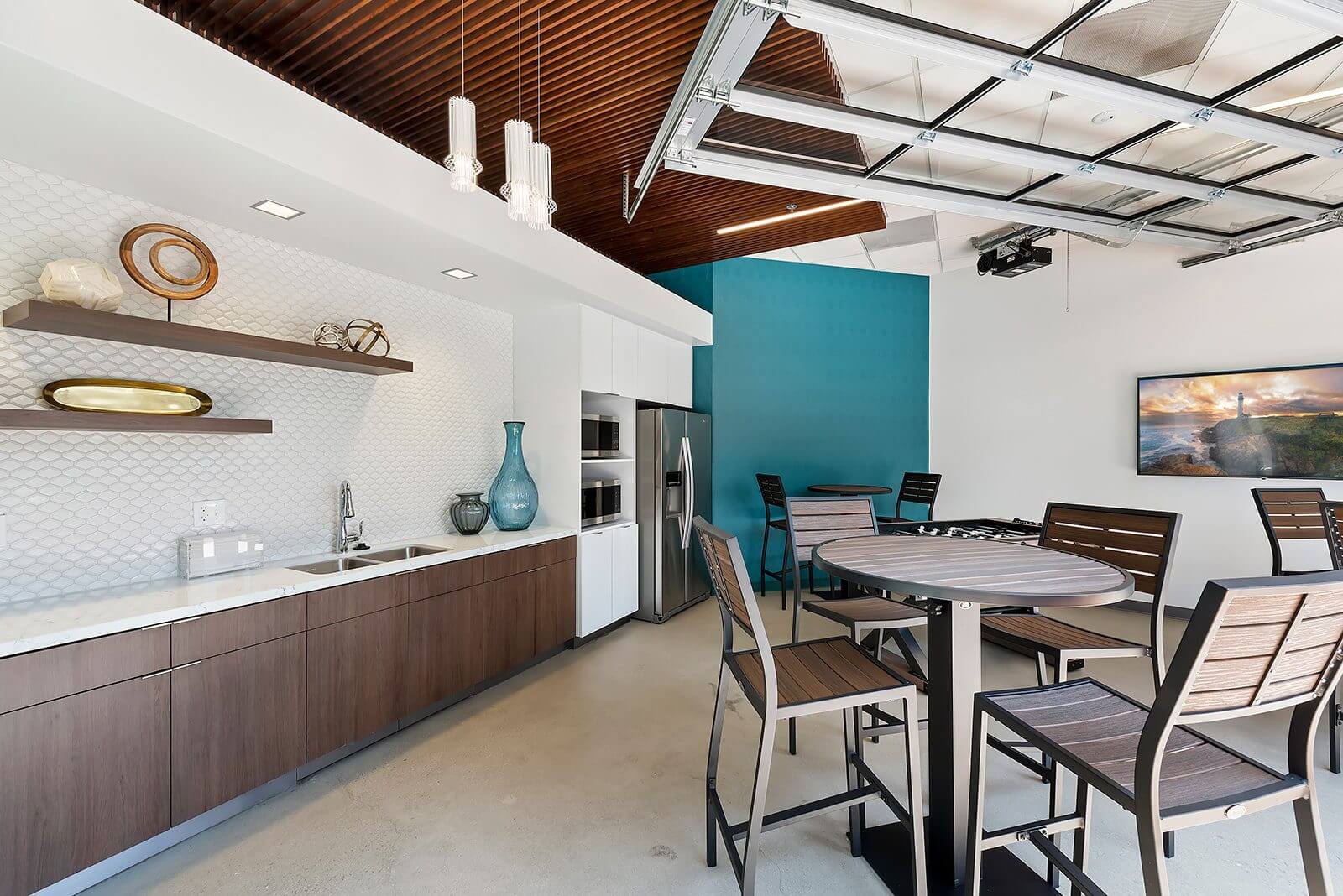 Modern kitchen and dining area with wooden ceiling and blue accent wall.